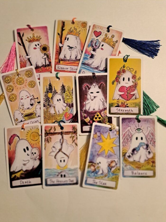 An image of several tarot cards decorated cartoon ghosts and black tassels.