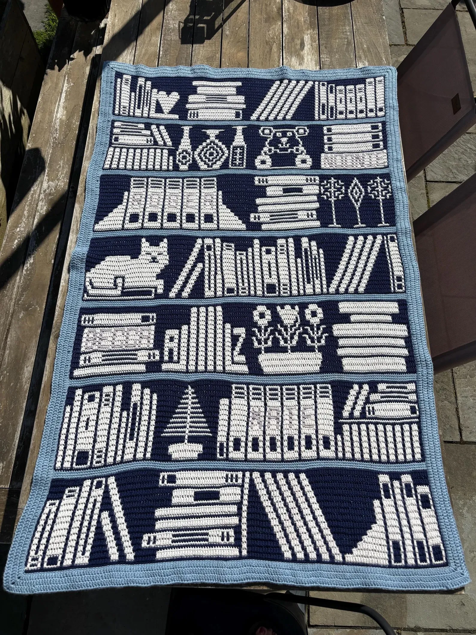 Bookshelf crochet blanket on wood floor.