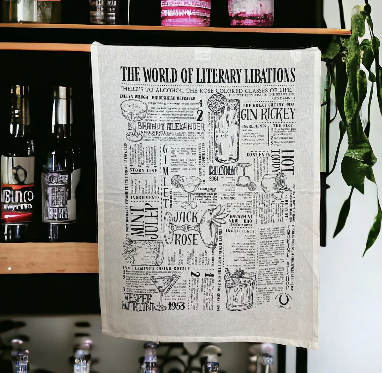 Image of a white tea towel with black cocktail illustrations, descriptions, and recipes from classic books