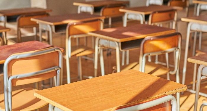 an empty classroom filled with wooden desks and chairs