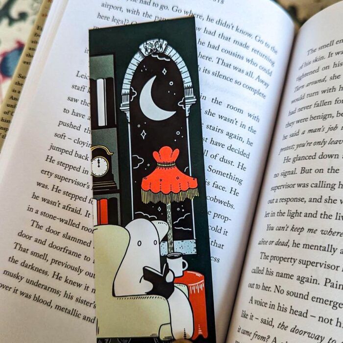 a bookmark with a cozy scene of a ghost reading in a living room, all in shades of white, black, and orange