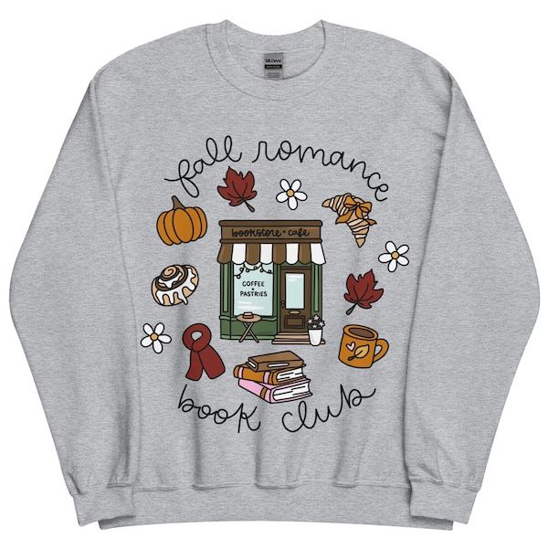 light grey crewneck sweater with a graphic of a bookstore and cafe on the front. Bordering the image is black cursive script that reads "fall romance book club" as well as assorted fall-themed graphics, like pastries, pumpkins, book stacks, and leaves