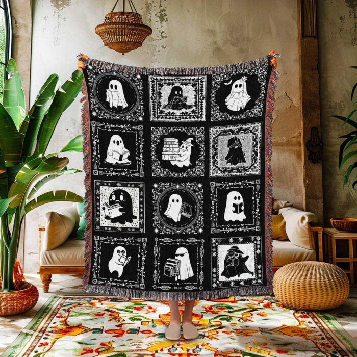 Image of a person holding a throw blanket on display in a cozy looking living room. The blanket has a pattern of squares with cartoon ghosts reading in different positions.