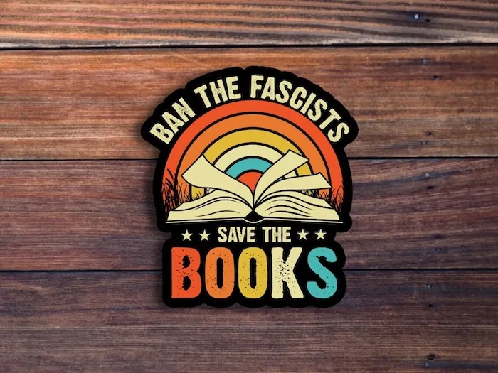 a sticker that says Ban the Fascists Save the Books. the text borders an open book in front of a rainbow