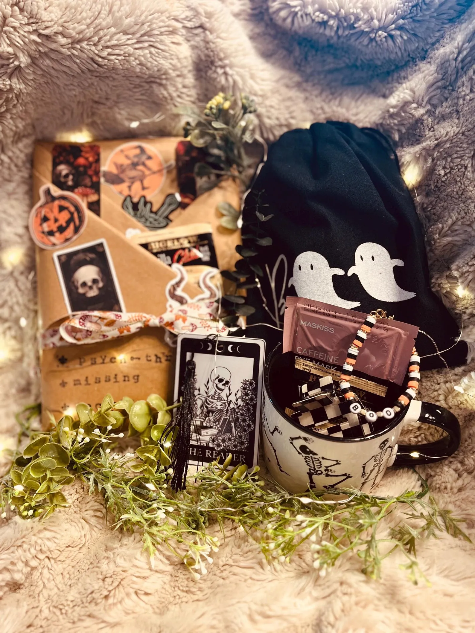 a wrapped book with stickers and stamped letters as well as a halloween mug, bracelet, tea, and hair clip