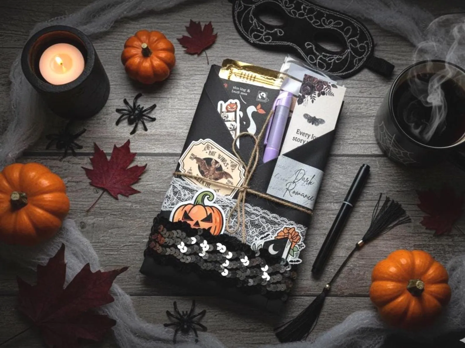 a book wrapped in black fabric and lace with stickers and a pen