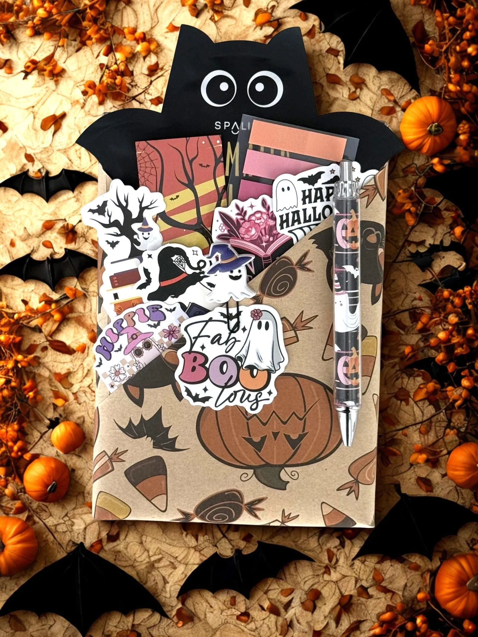 a book wrapped in halloween patterned paper with ghost stickers, pens, and bookmarks