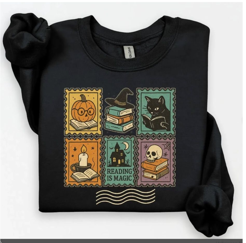 Image of a black sweatshirt that features what looks like 6 different stamps. Those "stamps" feature a black cat reading, a pumpkin reading, and other halloween imagery with books. 