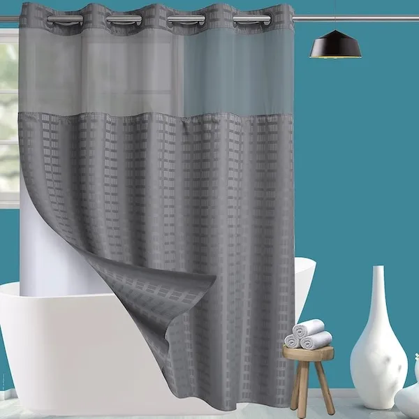 dark grey fabric shower curtain with a corner peeled back to reveal a white inner liner