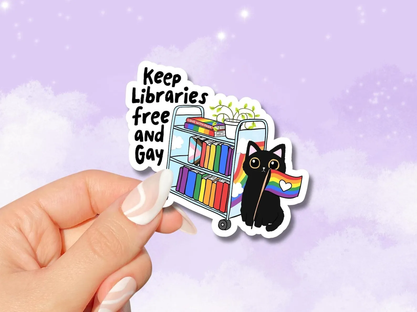 a sticker of a rainbow library cart, a cat, and a rainbow flag with the text Keep Libraries Free and Gay