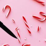 image of a hand holding a knife next to a broken candy cane