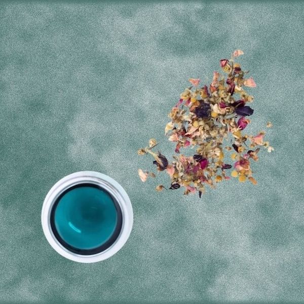 loose leaf floral tea and a white cup full of blue liquid