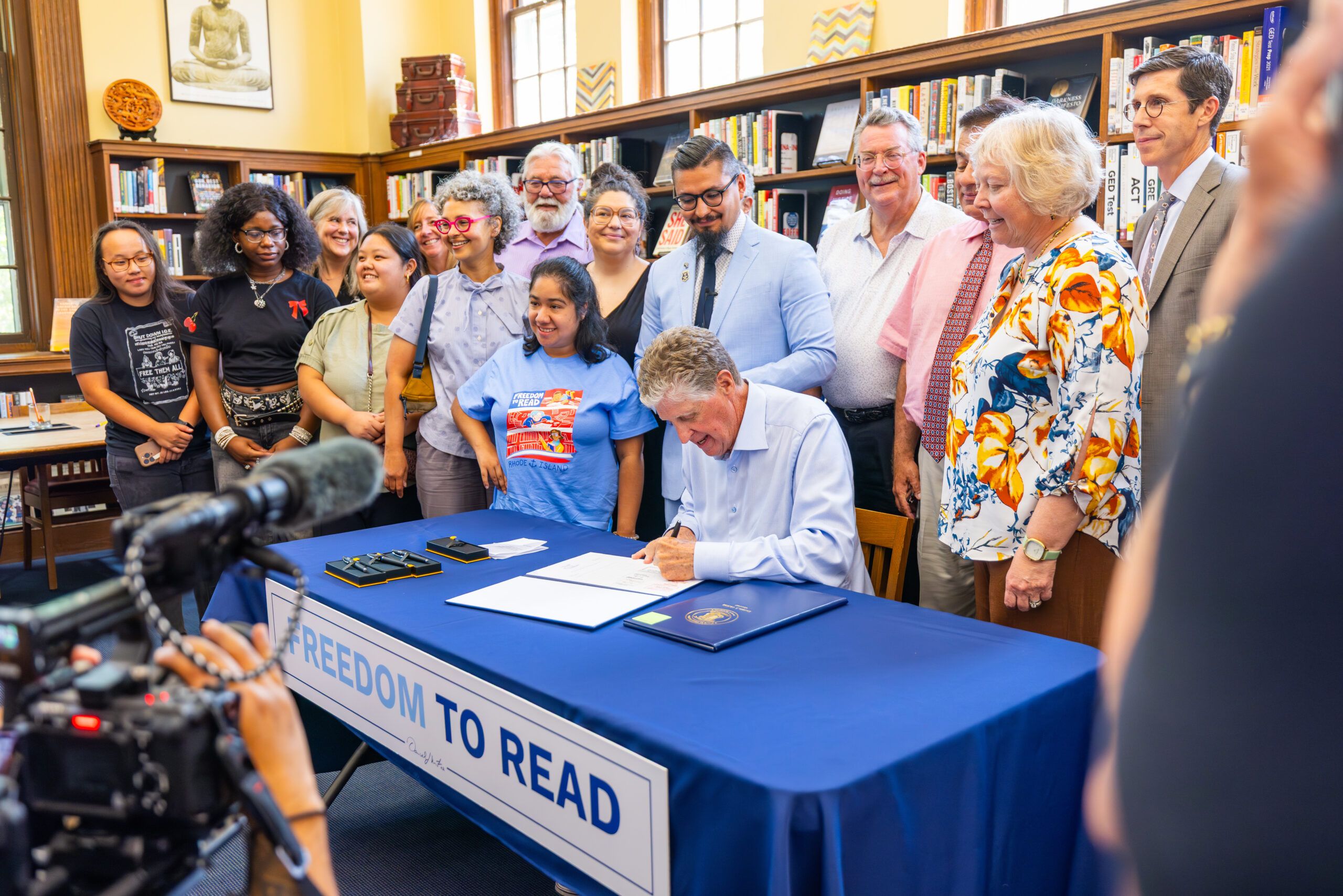 Image of Rhode Island freedom to read advocates watching as the governor signs the state's anti-book ban law.