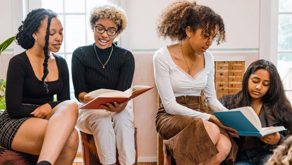 a group of young Black and Brown women reading and talking together