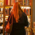 a person with long hair seen from behind, browsing a bookstore