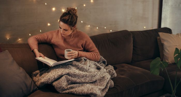 a woman with light skin reading in a cozy living room